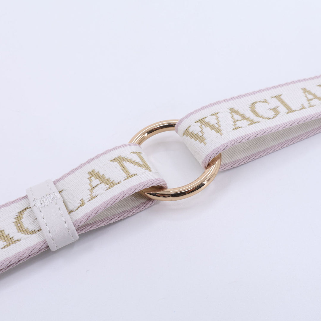 Close-up of a luxury dog leash featuring ivory and blush woven strap with gold or brown “WAGLANE” lettering, connected by a polished gold metal ring and white leather size adjuster detailing.